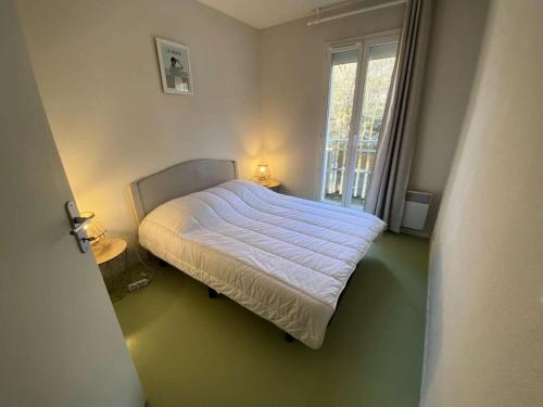 - une petite chambre avec un lit et une fenêtre dans l'établissement Résidence Domaine Des Sables - 052 - Maison mitoyenne agréablement située au cœur d'un parc boisé MAE-3621, à Soulac-sur-Mer