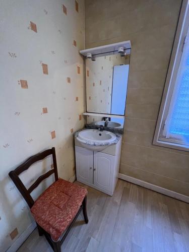 La salle de bains est pourvue d'un lavabo, d'une chaise et d'un miroir. dans l'établissement Résidence 056-soulac Sur Mer - 056 - Charmante villa Soulacaise à 2 pas du centre-ville MAE-3631, à Soulac-sur-Mer