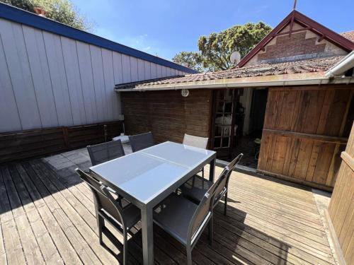 une table et des chaises sur une terrasse en bois dans l'établissement Résidence 056-soulac Sur Mer - 056 - Charmante villa Soulacaise à 2 pas du centre-ville MAE-3631, à Soulac-sur-Mer