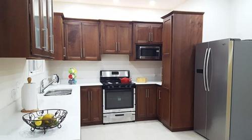 a kitchen with wooden cabinets and a refrigerator at Villa Devica in Bon Accord Village