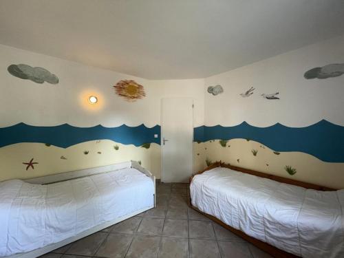- une chambre avec 2 lits et une fresque murale sur les vagues dans l'établissement Résidence 060-soulac Sur Mer - 060 - Agréable maison avec jardin à Soulac/mer MAE-3641, à Soulac-sur-Mer
