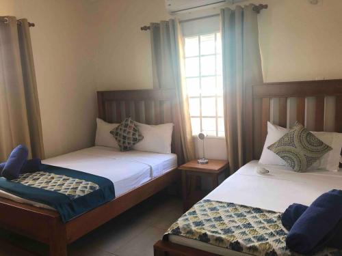 a bedroom with two beds and two windows at Villa Devica in Bon Accord Village