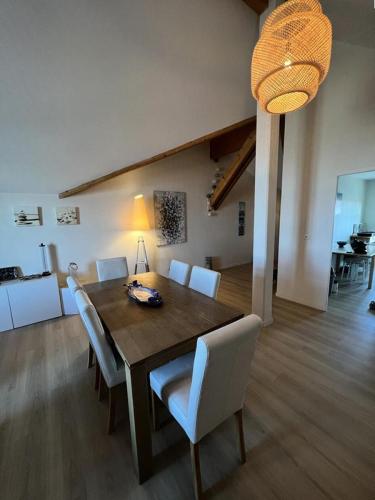 une salle à manger avec une table en bois et des chaises blanches dans l'établissement Résidence Le Clos Des Baïnes - 047 - Magnifique appartement classée 3 avec vue sur l'océan MAE-9651, à Soulac-sur-Mer