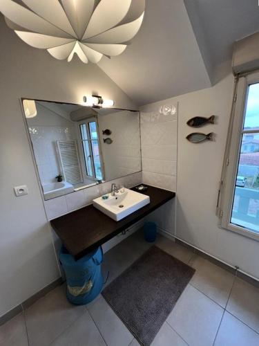 une salle de bain avec un lavabo et un miroir dans l'établissement Résidence Le Clos Des Baïnes - 047 - Magnifique appartement classée 3 avec vue sur l'océan MAE-9651, à Soulac-sur-Mer