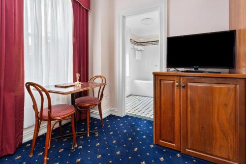 a hotel room with a television and a table and chairs at Palais Royale in Katoomba