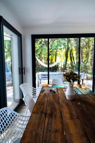 une salle à manger avec une table en bois et des chaises blanches dans l'établissement Résidence 081-soulac Sur Mer - 081 - Magnifique maison dans quartier prisé de Soulac MAE-9701, à Soulac-sur-Mer