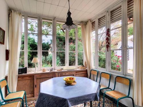 une salle à manger avec une table, des chaises et des fenêtres dans l'établissement Résidence 055-soulac Sur Mer - 055 - Jolie maison proche du centre-ville MAE-1861, à Soulac-sur-Mer