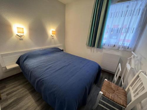 une chambre avec un lit bleu et une fenêtre dans l'établissement Résidence Les Vertmarines - 074 - Appartement dans une résidence privée avec piscine MAE-4151, au Le Verdon-sur-Mer