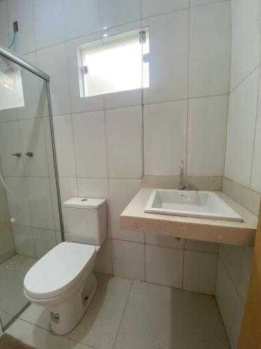 a white bathroom with a toilet and a sink at Pousada Vila Artesão in Resende Costa