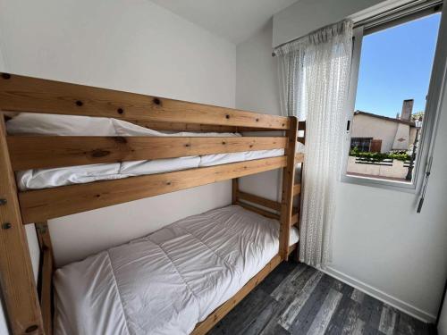 une chambre avec deux lits superposés et une fenêtre dans l'établissement Résidence Cap Atlantic - 066 - Bel appartement en rez-de-jardin à quelques pas de la plage MAE-1971, à Soulac-sur-Mer