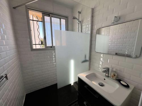 une salle de bain blanche avec un lavabo et un miroir dans l'établissement Résidence Cap Atlantic - 066 - Bel appartement en rez-de-jardin à quelques pas de la plage MAE-1971, à Soulac-sur-Mer