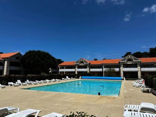 une grande piscine avec des chaises et un bâtiment dans l'établissement Résidence Le Cordouan - 116 - Bel appartement rénové avec goût dans une résidence 3 MAE-2881, à Soulac-sur-Mer