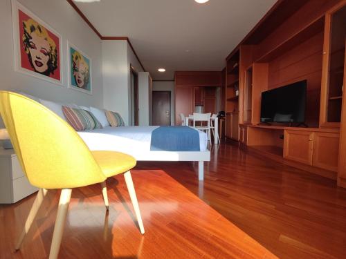 ein Schlafzimmer mit einem Bett und zwei Stühlen und einem Fernseher in der Unterkunft Jasmine Golf & Malpensa, studio in Robinie club in Solbiate Olona