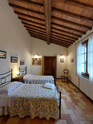 a bedroom with two beds and a wooden ceiling at Agriturismo Corte in Poggio in Stabbia