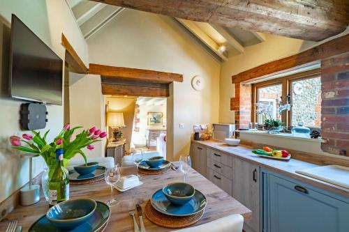 a kitchen with a wooden table with plates on it at Newly Refurb Cottage, Mile From Blakeney, Village Pub and Restaurant in Langham
