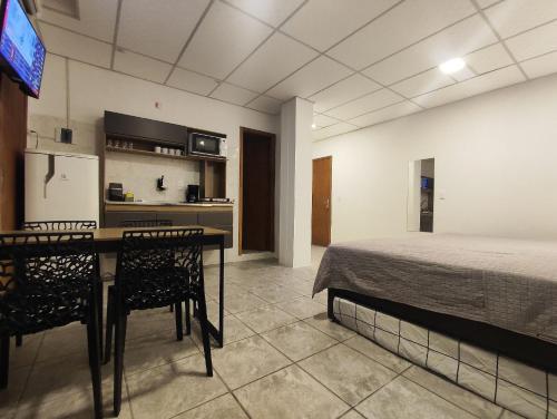 a bedroom with a bed and a table and chairs at Villa Bilac - Amplos Studios 2km da Vila Germânica in Blumenau