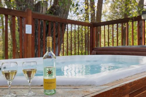 een fles wijn en twee wijnglazen naast een hot tub bij Teton Serenity in Driggs