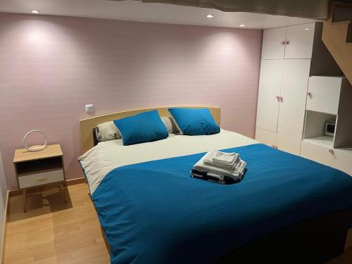 une chambre avec un grand lit avec des oreillers bleus dans l'établissement Maison type Villa avec piscine à 400 m du circuit des 24h, au Mans