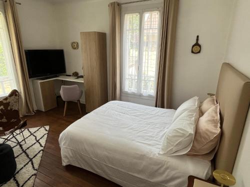 a bedroom with a white bed and a television at Chambre villa du sentier in Pomponne