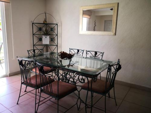 a glass dining room table with chairs and a mirror at Marina Independence - Dpto K-01 in Acapulco