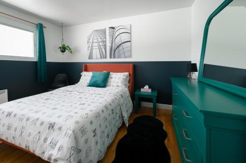 a bedroom with a bed and a dresser and a television at La Maison du Sentier - Foyer et Mt Porphyre in Murdochville