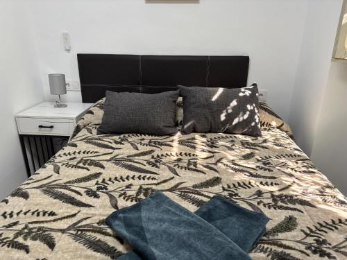 a bedroom with a bed with a black headboard and pillows at Alojamientos Capri in Quesada