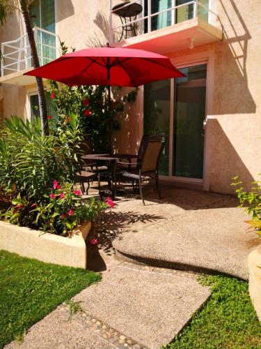 a patio with a table and a red umbrella at Marina Independence - Dpto K-01 in Acapulco