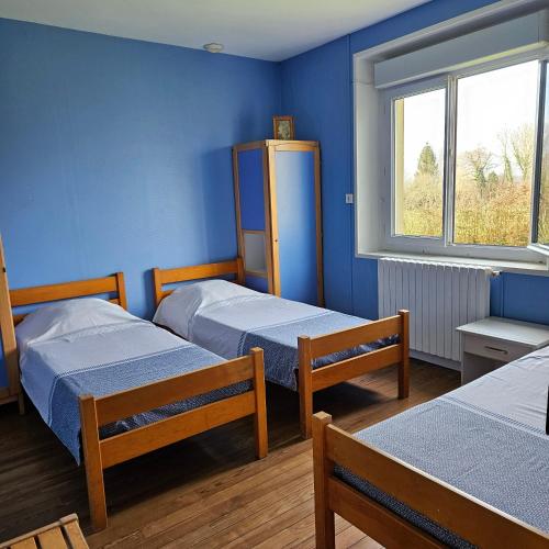 two beds in a room with blue walls at Gîtes de la terrette in Tribehou
