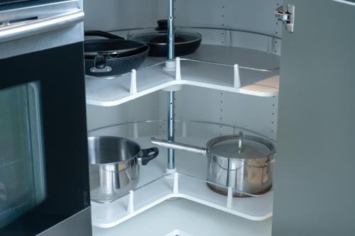 a kitchen with two pots and pans on shelves at La Kobber Hüs - Élégance au coeur de la ville in Murdochville