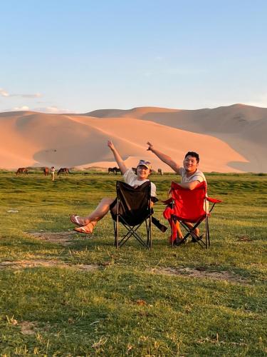 two people sitting in folding chairs in a field at Gobi-Girl in Ulaanbaatar