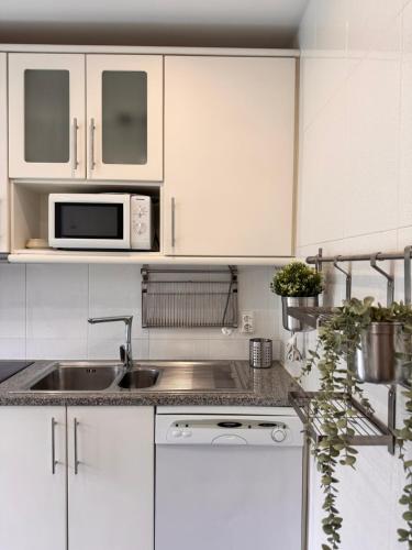 a white kitchen with a sink and a microwave at Refúgio Suave Mar in Esposende