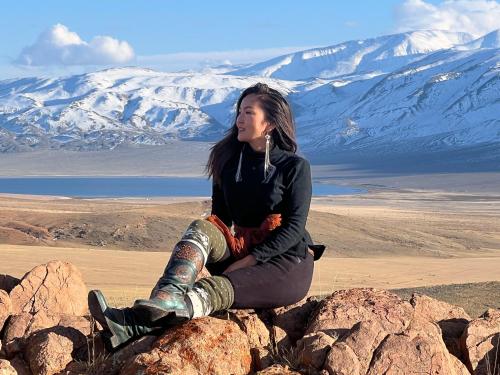 a woman sitting on a rock with mountains in the background at Gobi-Girl in Ulaanbaatar