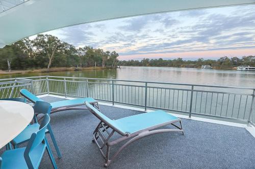 a balcony with chairs and a table and a view of a river at All Seasons Houseboats in Mildura