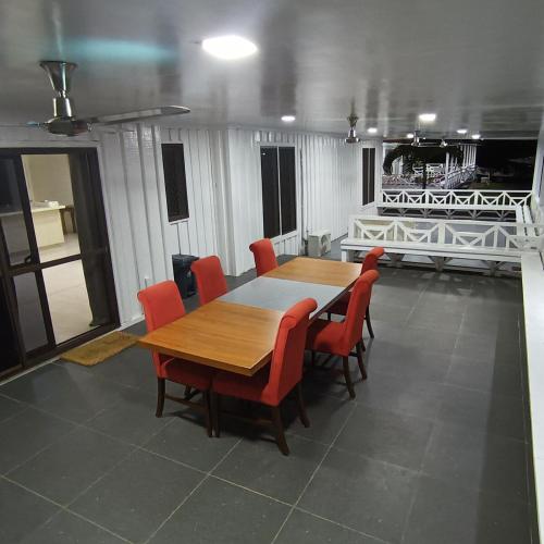 a dining room with a wooden table and red chairs at Taumeasina Coconut Terrace Villa 1 in Apia
