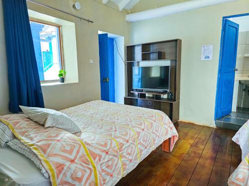 Un dormitorio con una cama y un televisor de pantalla plana. en Hospedaje Euro's De San Blas, en Cusco