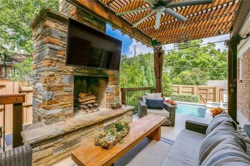 Una sala de estar al aire libre con chimenea de piedra y televisión. en E Dallas Family Home with Pool Spa Outdoor Fire, en Dallas