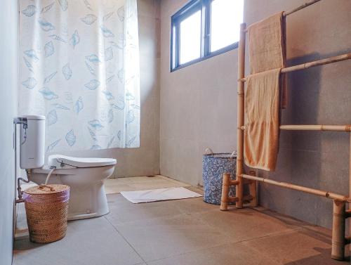 a bathroom with a toilet and a window at Umah Adenium Ubud 2 in Tegalalang