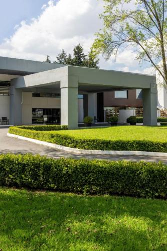 a large building with a green lawn in front of it at Courtyard Toluca Airport in Toluca