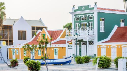 a row of colorful buildings with a boat in front at Eagle Stays Aruba-NEW Luxury, Cozy & Spacious Studio Near Eagle Beach! in Oranjestad