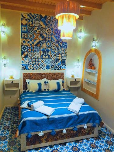 a bedroom with a blue bed with a blue patterned wall at Dar Milal in Essaouira