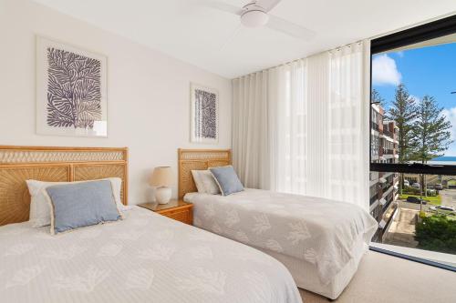 two beds in a bedroom with a large window at Sol 803 in Gold Coast
