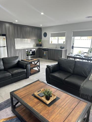 a living room with black couches and a table at Lbarza New Exec 3BR Townhouse walk to shopping centre in Kialla