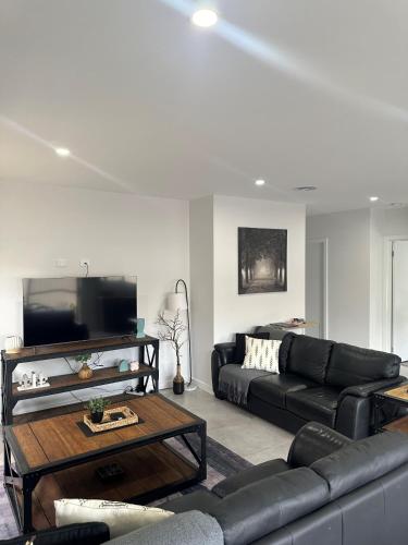 a living room with a black couch and a tv at Lbarza New Exec 3BR Townhouse walk to shopping centre in Kialla