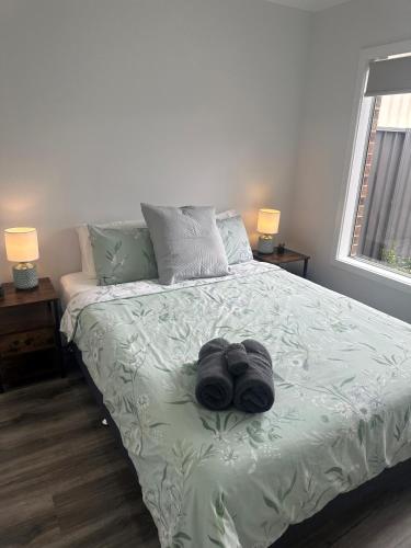 a bed with two pairs of shoes on it at Lbarza New Exec 3BR Townhouse walk to shopping centre in Kialla