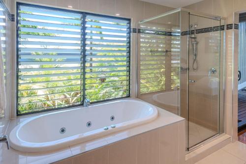 a bathroom with a tub and a shower and a window at Pinnacle Apartments on Hamilton Island by HIHA in Hamilton Island