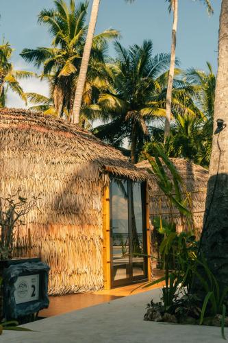 a straw hut with a yellow door and palm trees at The Dome Hotel Puerto Princesa City in Puerto Princesa City