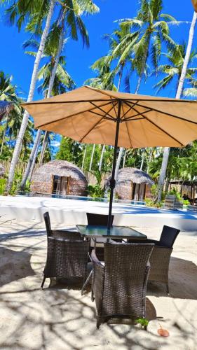 a table and chairs with an umbrella on the beach at The Dome Hotel Puerto Princesa City in Puerto Princesa City