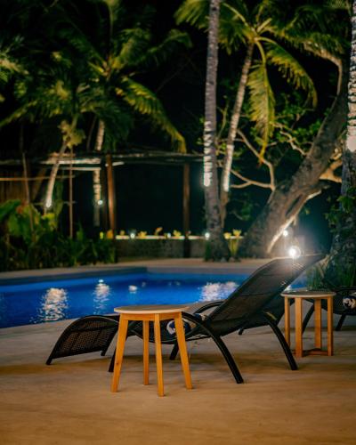 a table and chairs next to a pool at night at The Dome Hotel Puerto Princesa City in Puerto Princesa City