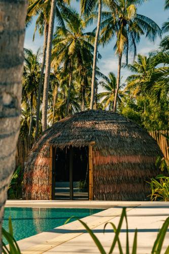 a thatched hut next to a pool with palm trees at The Dome Hotel Puerto Princesa City in Puerto Princesa City