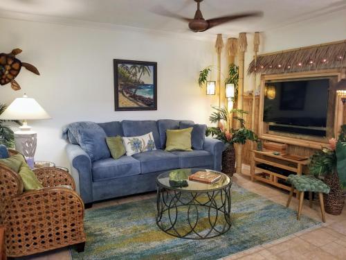 Una sala de estar con un sofá azul y un televisor. en Tiki Hale Lua at the Surf and Racquet Club, en Kailua-Kona